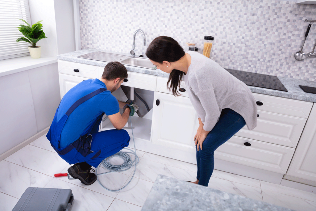 Plumber snaking woman's kitchen sink.